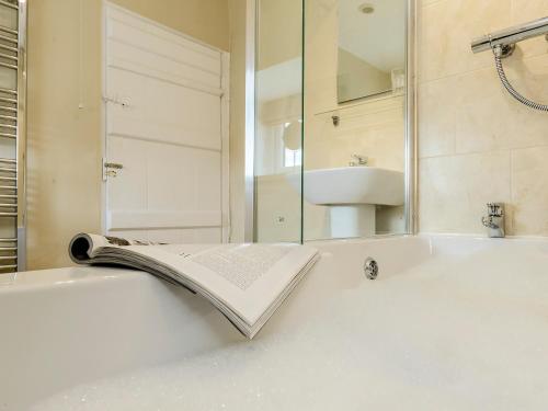 La salle de bains est pourvue d'un lavabo et d'un livre sur une baignoire. dans l'établissement Backstone Bank Farmhouse, à Wolsingham