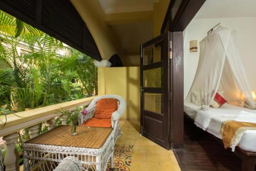 Habitación con balcón, cama y mesa. en Marirath Boutique Hotel, en Siem Reap