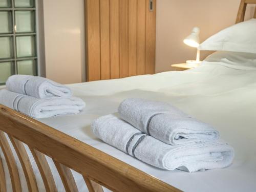 un grupo de toallas sentadas encima de una cama en Stack View Cottage en Holyhead