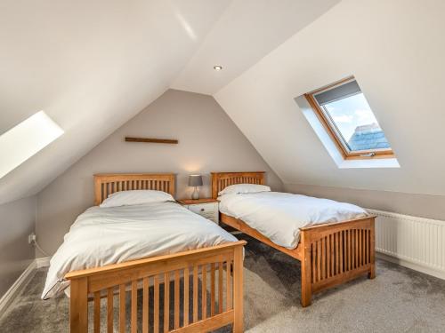 two beds in a attic bedroom with a window at Stack View Cottage in Holyhead