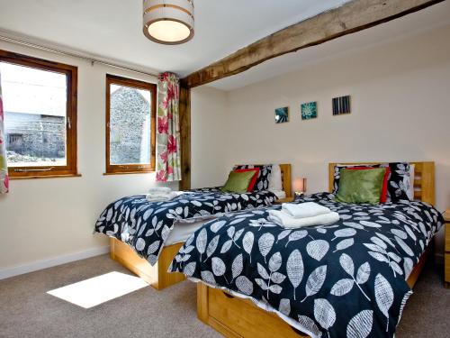 two beds in a room with two windows at Blackbird Cottage in Kings Nympton