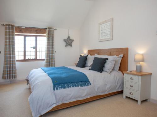 a bedroom with a large bed with a blue blanket at Little Nymett in North Tawton