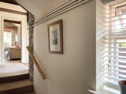 a hallway with a picture on the wall and a stairway at Dairy Cottage in Abergavenny