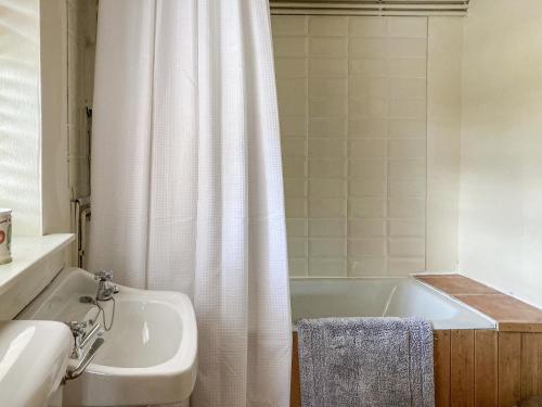 a bathroom with a white shower curtain and a sink at Dairy Cottage in Abergavenny