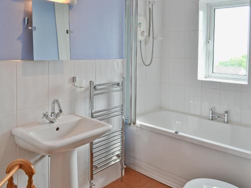 a bathroom with a sink and a tub and a toilet at Millford House in Hartland