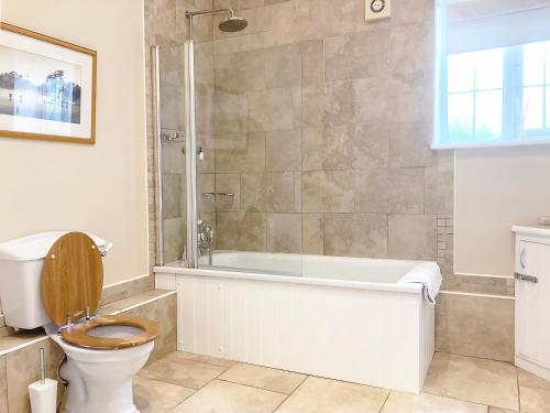 ein Badezimmer mit einem WC, einer Badewanne und einer Dusche in der Unterkunft Valley Farm Cottage in Sudbourne