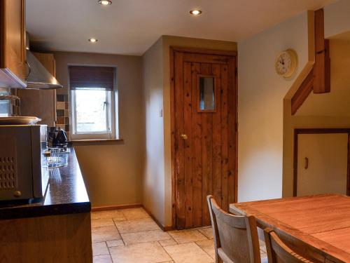 a kitchen with a table and a wooden door at The Cot in Chalford