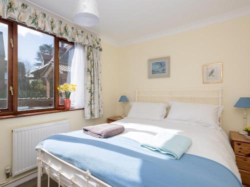 a bedroom with a large bed with a window at Seagulls in Blakeney