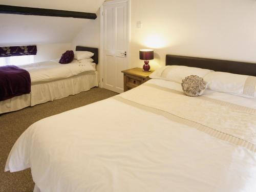 a bedroom with two beds and a table with a lamp at Deuglawdd Cottage - Hw7788 in Aberdaron