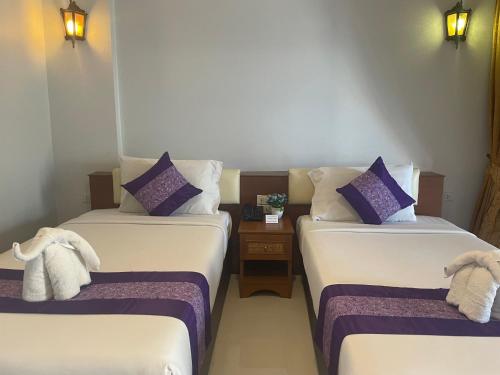 a room with two beds with purple and white pillows at Embryo Hotel  in Pattaya Central