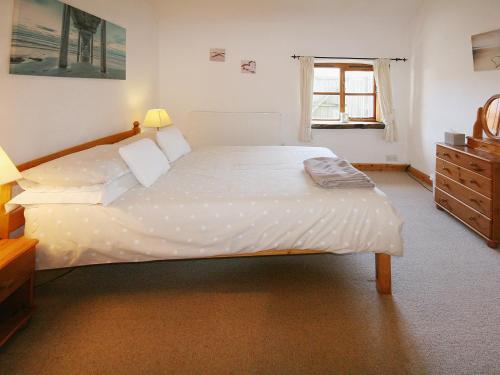 a large white bed in a bedroom with a window at The Willows in Parkmill