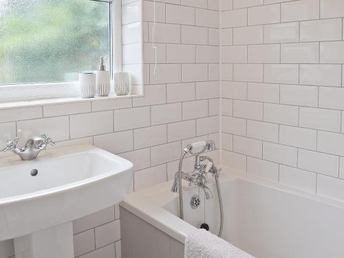 a white bathroom with a sink and a bath tub at Albion Cottage in Pakefield