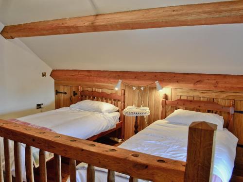 two beds in a room with wooden walls at Tre Fardre in Kinmel