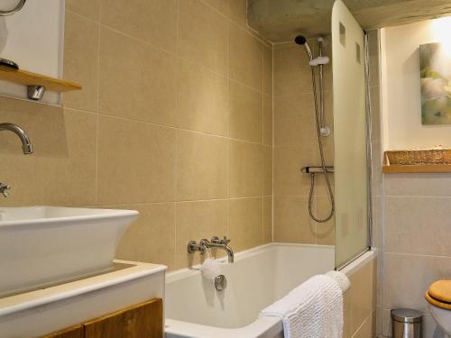 y baño con bañera, lavamanos y ducha. en Oak Cottage en Woolfardisworthy
