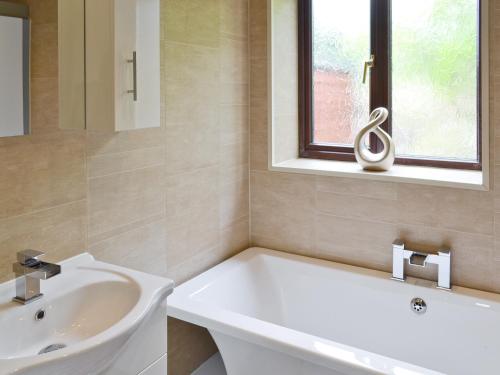 a bathroom with a tub and a sink and a window at Bellwood House Annexe in Felixkirk