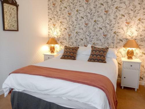 een slaapkamer met een groot wit bed met 2 lampen bij Tarandoun Cottage in Helensburgh