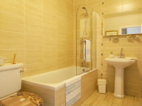 een badkamer met een bad, een toilet en een wastafel bij Tarandoun Cottage in Helensburgh