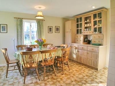 a dining room with a table and chairs and a kitchen at Dhuallow in Aberarder