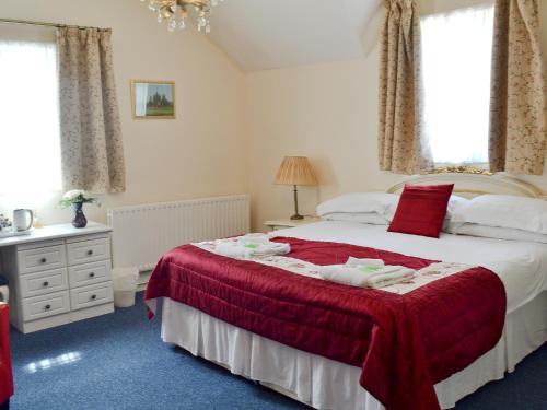 a bedroom with a bed with a red blanket at The Farmhouse in Hampreston