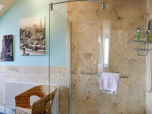 a bathroom with a glass shower with a chair at South Cliff Sands Ii in Scarborough