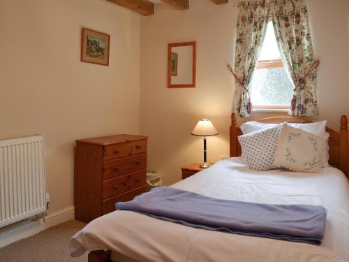 sypialnia z łóżkiem z oknem i komodą w obiekcie Brampton Hill Farm Cottage w mieście Madley