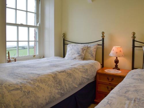a bedroom with a bed and a window at Downhouse Cottage in Delabole