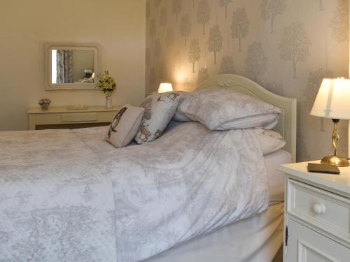 ein Schlafzimmer mit einem weißen Bett mit Kissen und einem Spiegel in der Unterkunft The Secret Garden in Windermere