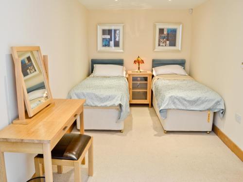 two beds in a room with a desk and a table at The Old Mill - 28218 in Thropton