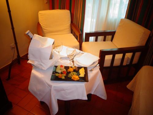 a table with a plate of fruit and glasses on it at Parador de Manzanares in Manzanares