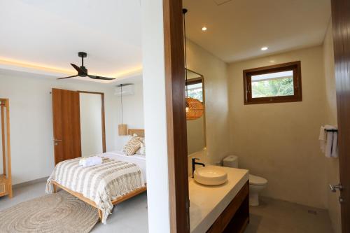 a bedroom with a bed and a sink and a mirror at Shoreline Villas Bingin in Uluwatu