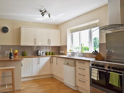 a kitchen with white cabinets and a window at Baswick Steer in Burshill