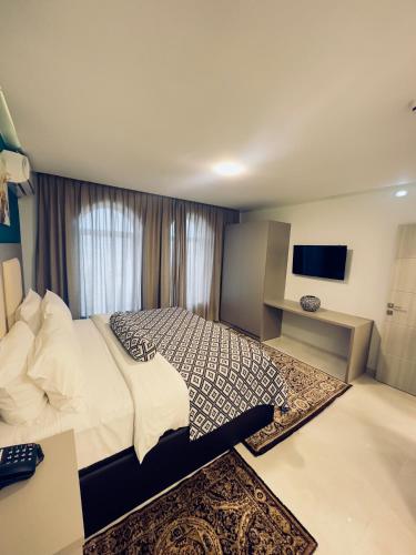 a bedroom with a bed and a desk and a television at Olive Tree Amman in Amman