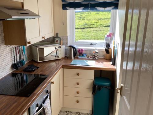 una piccola cucina con lavandino e forno a microonde di Mark Close Milking Parlour ad Alston