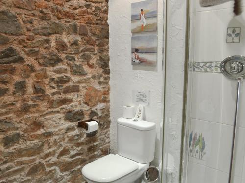 a bathroom with a white toilet and a stone wall at The Garden Room - 15536 in Marldon
