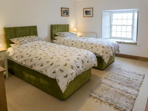 a bedroom with two beds and a window at Chapel Cottage in Askham