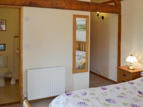 1 dormitorio con cama y espejo en Orchard View Barn en Plymtree