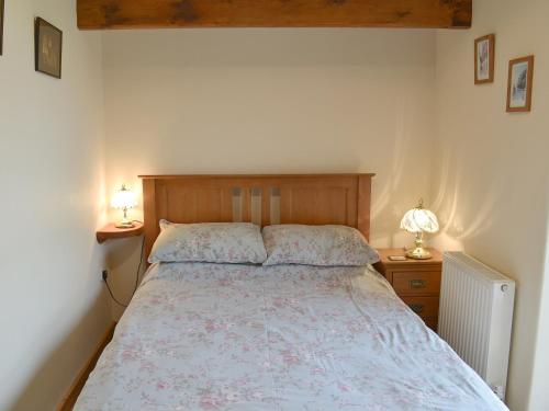 a bedroom with a bed and two night stands with lamps at Orchard View Barn in Plymtree