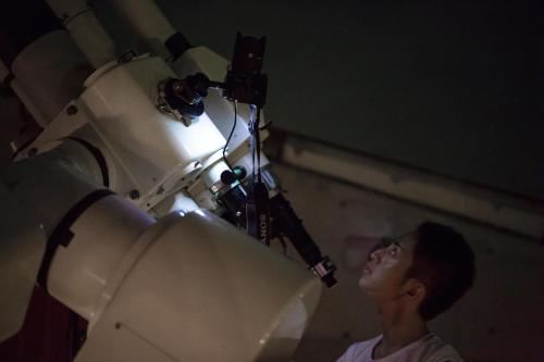 a man standing in front of a camera next to a telescope at Minami Aso Luna Observatory Auberge Mori no Atelier in Minami Aso