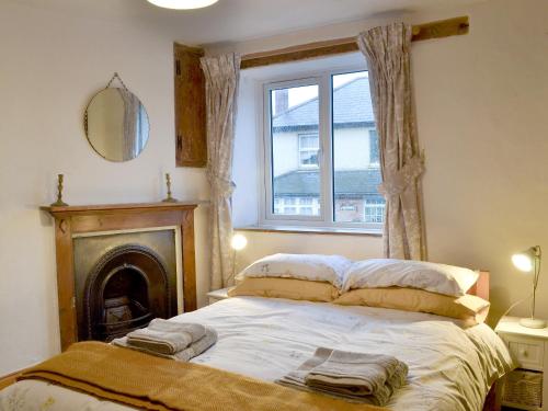 a bedroom with a bed with a fireplace and a window at Lamont Cottage in Niton