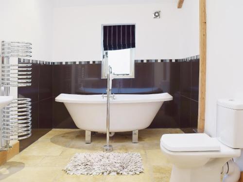 a bathroom with a bath tub and a toilet at Hobland Barn in Belton