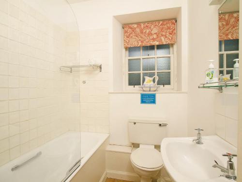 a bathroom with a toilet and a tub and a sink at Stables Cottage-uud in Corsock