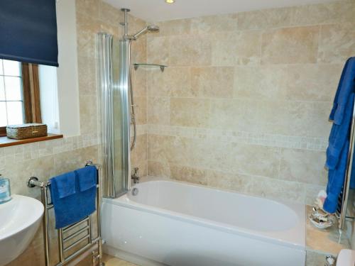y baño con bañera blanca y lavamanos. en Oast Cottage en Herstmonceux