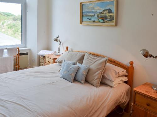 Un dormitorio con una cama blanca con almohadas. en Tamarisk en Coverack