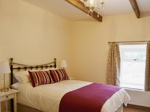 a bedroom with a bed and a window at The Byres in Greenhaugh