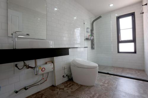 a white bathroom with a toilet and a sink at TarTar & Nay Hostel in Chiang Mai