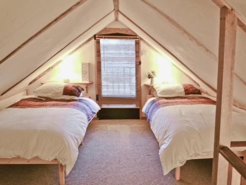 two beds in a room with a pointed roof at Byre Cottage - 29410 in Elmsted