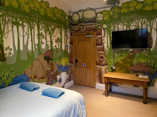 a bedroom with a wall with a mural of a forest at The Full Moon Backpackers in Bristol