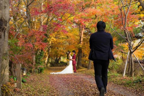 a bride and groom walking down a path in the woods at Minami Aso Luna Observatory Auberge Mori no Atelier in Minami Aso