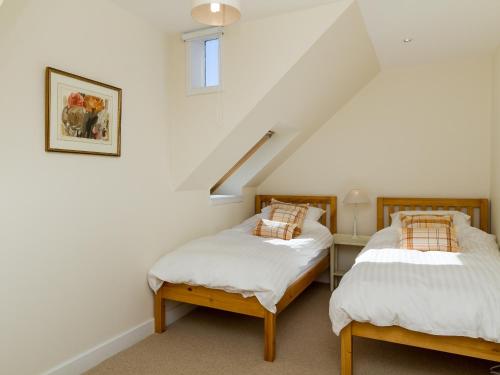 two twin beds in a room with a staircase at Two The Stables in Dalrymple