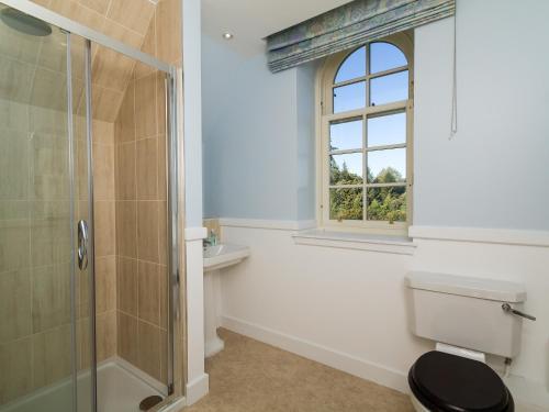 a bathroom with a shower and a toilet and a window at Two The Stables in Dalrymple